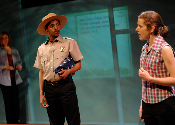 three actors on stage, two dressed as civilians and one in police uniform